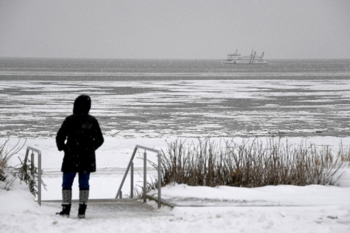 Eine Fußgängerin steht am Strand im Schnee. (Symbolbild)