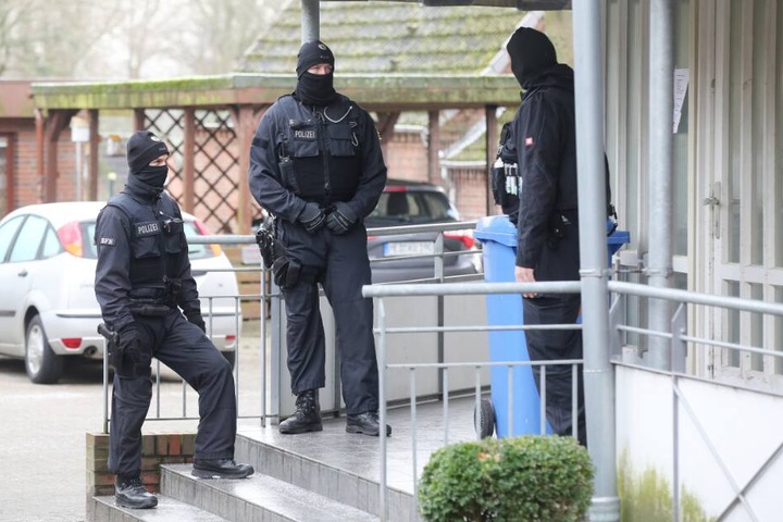 Einsatzkräfte der Polizei stehen während einer Durchsuchung vor einem Haus im Kreis Dithmarschen.