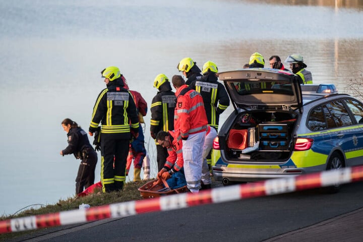 Einsatzkräfte der Polizei und Feuerwehr stehen an einem Gewässer. (Symbolfoto)