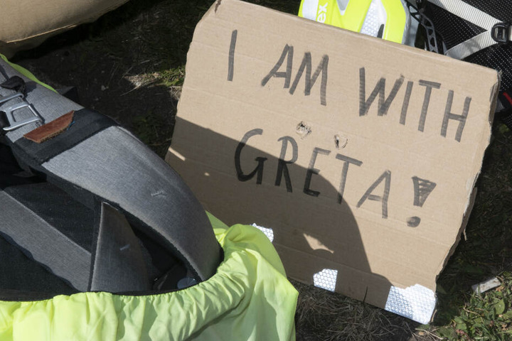 Ein Schild mit der Aufschrift "I am with Greta" liegt neben einem Rucksack.