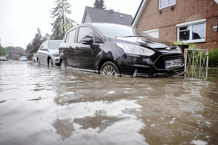 Autos stehen auf einer Überfluteten Straße in Hamburg-Bergedorf.