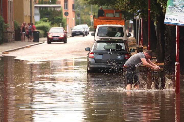 Nach dem Sturzregen watet ein Freitaler durch das tiefe Wasser.