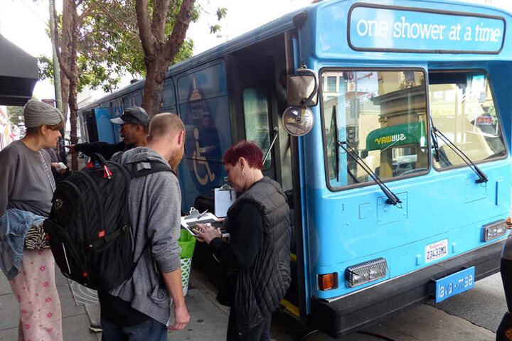 Obdachlose werden in San Francisco in die Warteliste für den mobilen Dusch-Bus mit der Aufschrift "One Shower at a Time" eingetragen.
