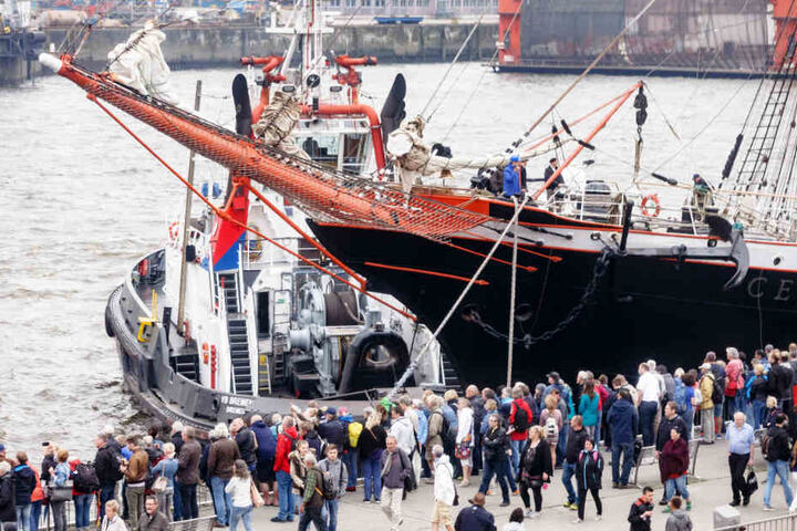Besucher des Hafengeburtstags beobachten nach der Einlaufparade das Anlegemanöver des russischen Großseglers Sedov an den Landungsbrücken.