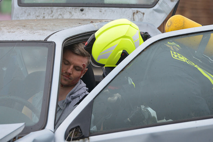 Eine Person ist scheinbar schwer verletzt im Fahrzeug eingeklemmt und muss von Rettungskräften geborgen werden.