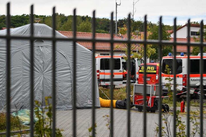 Fahrzeuge vom Katastrophenschutz, DLRG und dem Deutschen Roten Kreuz stehen auf dem Gelände der Bundespolizei in Frankfurt (Oder) neben einem Zelt, in dem eingeschleuste Menschen betreut werden.