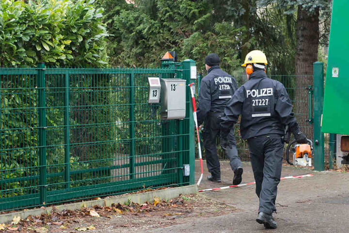 Polizisten betreten mit einer Motorsäge das Grundstück, auf welchem ein Einfamilienhaus eingestürzte.