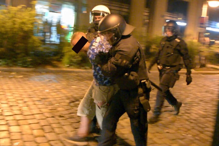 Polizisten führen einen der Krawallos ab.