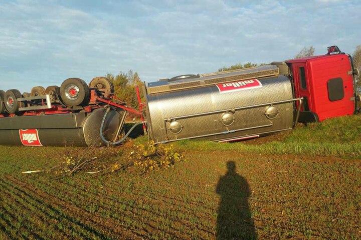 Der Laster liegt quer auf einem Feld.