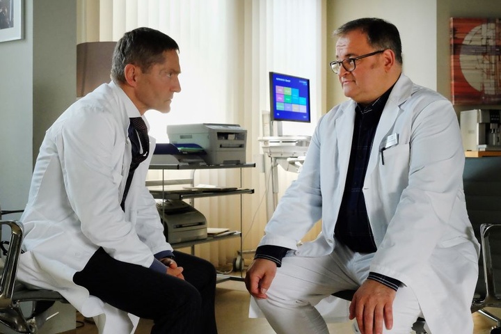 In einem persönlichen Gespräch teilt Hans-Peter Brenner (r.) Dr. Rolf Kaminski mit, dass er sich als Assistenzarzt der Urologie nicht mehr wohl fühlt und stattdessen in die Geriatrie wechseln will. Kaminski ist entsetzt.