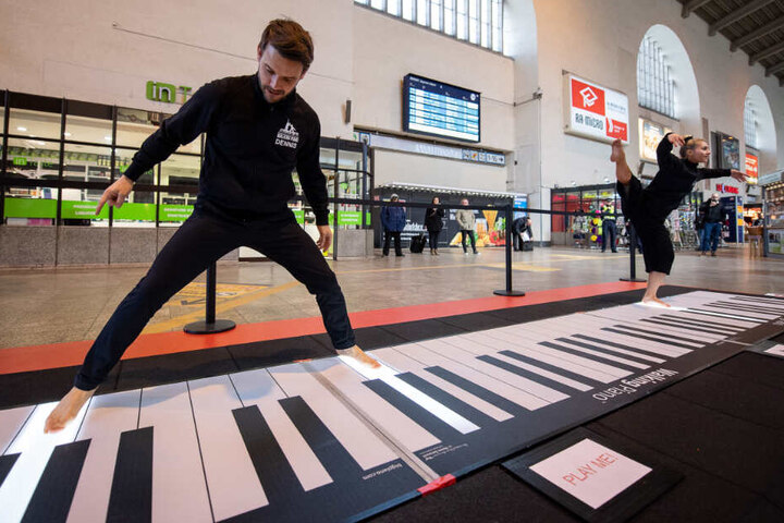 Leslie und Dennis spielen im Hauptbahnhof auf einem begehbaren Klavier.