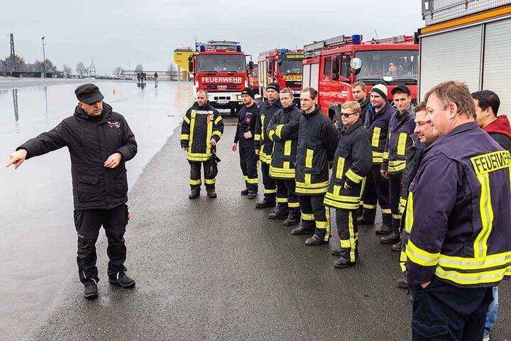 Alles klar? Fahrlehrer Sven Förster (52, u.l.) weist die Feuerwehr-Fahrer auf der Nass-Strecke ein.