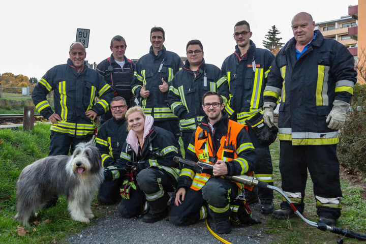 Die Feuerwehrleute posieren mit dem Vierbeiner.