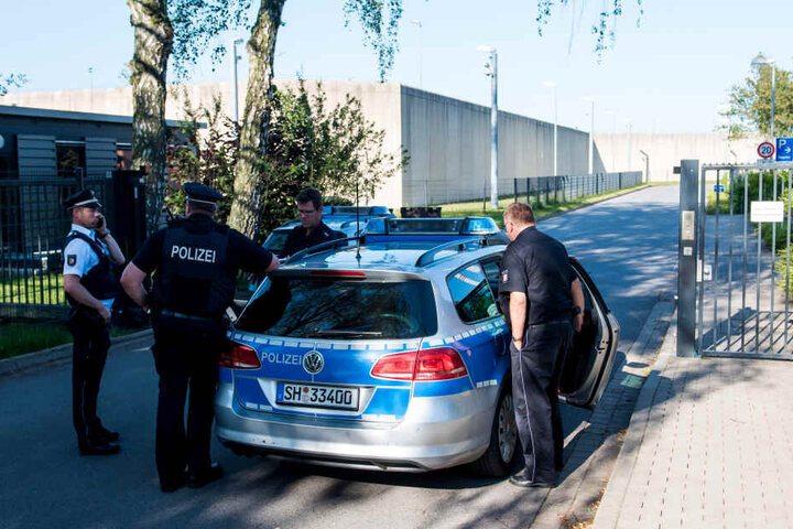 Polizeibeamte stehen vor der Justizvollzugsanstalt in Lübeck: Ein Geiselnehmer hat hier eine Frau in seine Gewalt gebracht, wie ein Sprecher des Justizministeriums erklärte.