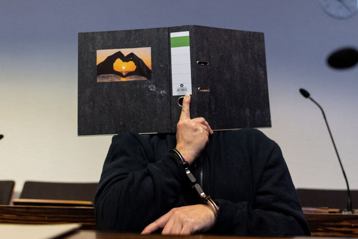 Bernhard H. (58) bedeckt sein Gesicht mit einem Aktenordner.