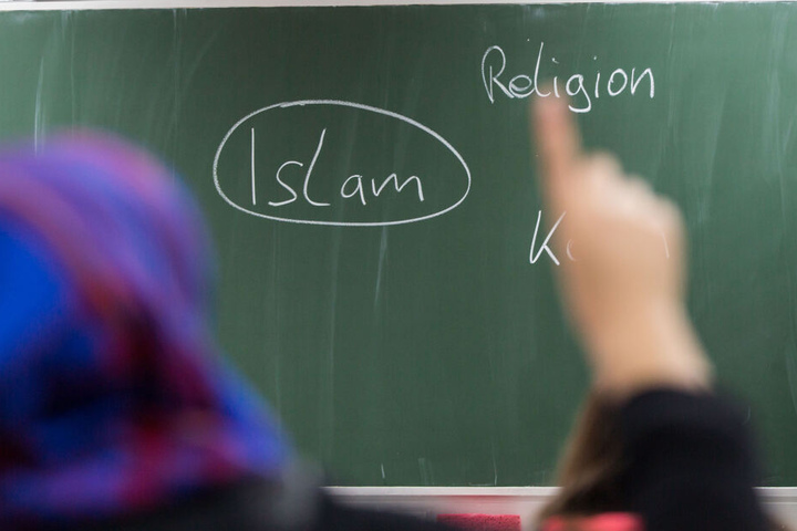 Eine Schülerin mit Kopftuch meldet sich an einer Schule bei einer Unterrichtsstunde zum Thema Islam.