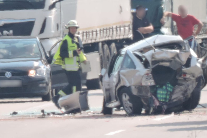 Ein Feuerwehrmann am Wrack eines Opel.