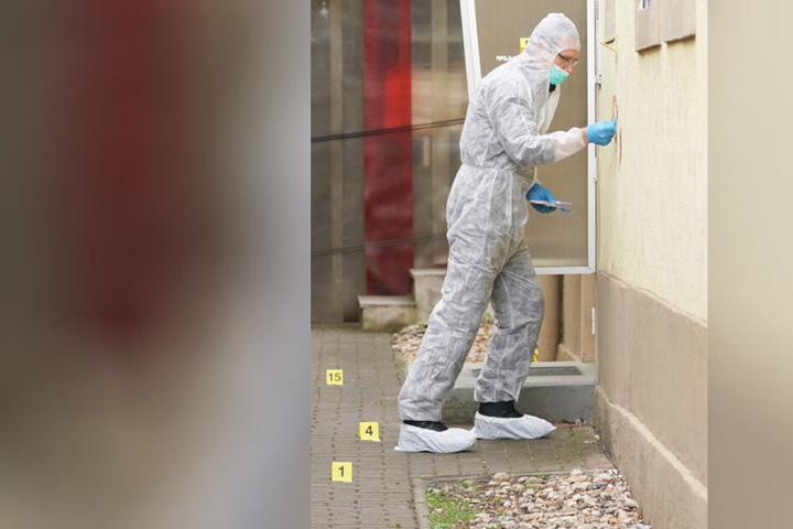 Ein Mitarbeiter der Spurensicherung an der Hauswand des benachbarten Gebäudes, in dem die Familie wohnte.