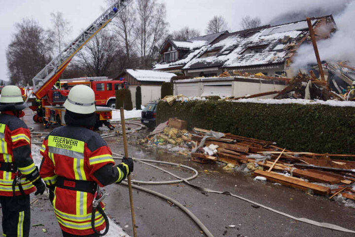 Zwei Feuerwehrleute stehen am Sonntag vor dem zerstörten Haus.