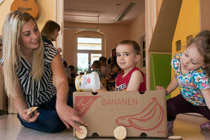 Brandley (3) und Mia (5) haben mit Erzieherin Jennifer Opp (28) einen Pappkarton zum Gefährt umgebaut.