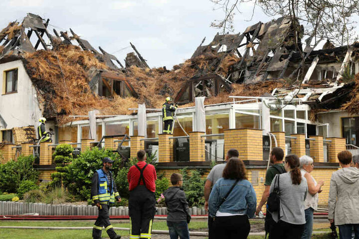 Urlauber und Feuerwehrleute betrachten das Hotelgebäude.
