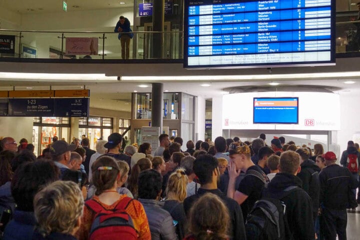 Reisende schauen auf einen Monitor im Hauptbahnhof von Nürnberg auf dem bedingt durch Sturmtief Fabienne auf Einschränkungen im Bahnverkehr hingewiesen wird.