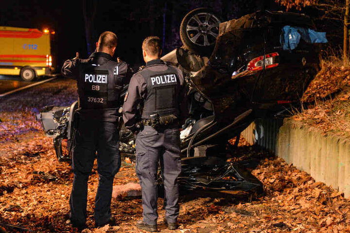 Polizisten betrachten den Unfallwagen.