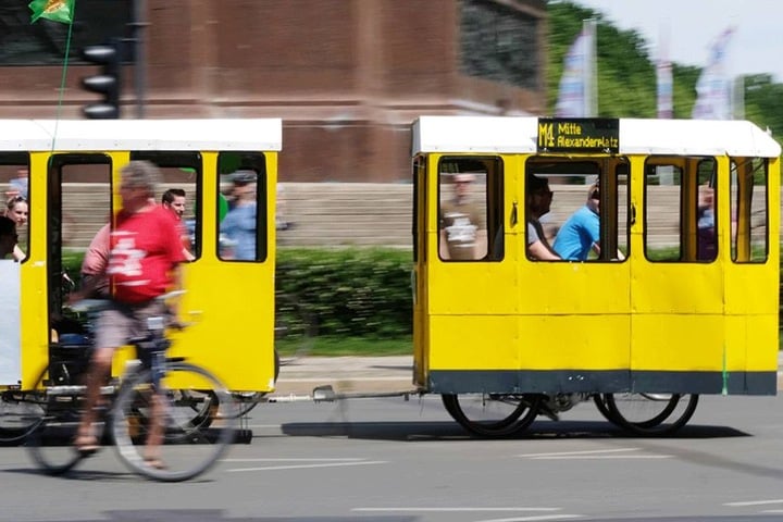 Fahrradfahrer mit einer nachgebildeten Straßenbahn fahren bei der Berliner Fahrradsternfahrt den Großen Stern entlang