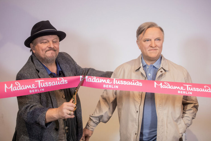 Axel Prahl schneidet ein rotes Band von Madame Tussauds durch.