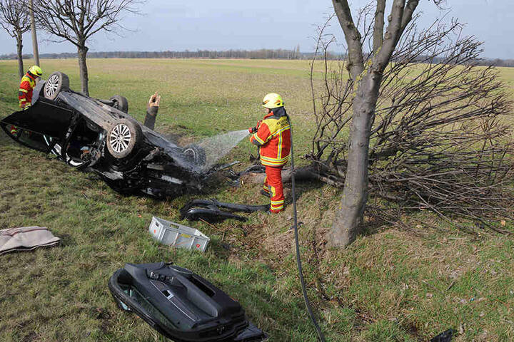 Einsatzkräfte der Feuerwehr an der Unfallstelle. Auf dem Bild auch zu sehen: der entzwei gebrochene Baum.