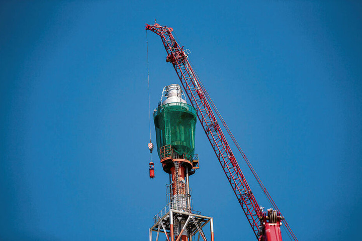 Ein Kran, der einen Hub von bis zu 160 Metern besitzt, unterstützt die Arbeiten am Fackelkopf. Hier bringt er Schlosser mit einer Gondel zu ihrem Job in gut 140 Meter Höhe.