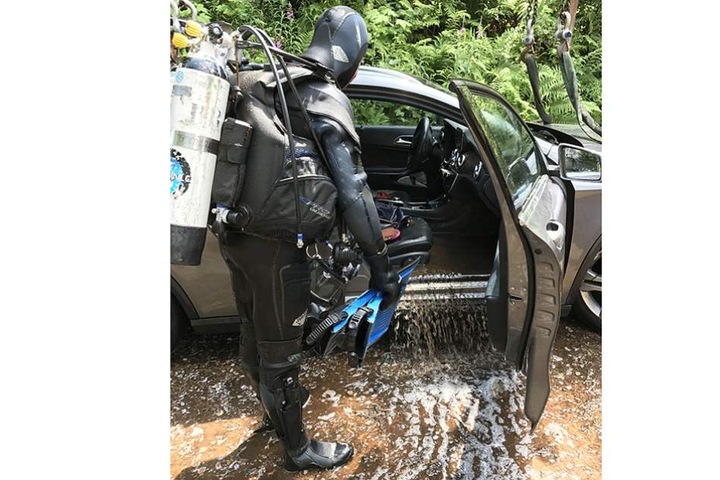 Ein Taucher steht neben dem geborgenen Mercedes.