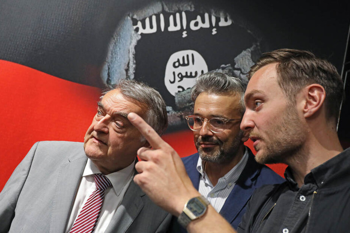 Herbert Reul (CDU, l-r), Innenminister von Nordrhein-Westfalen, Alexander Wipprecht und Orlando Klaus, Filmproduzenten der Firma BlueLaserBoys, sprechen auf dem Stand des Landesverfassungsschutzes auf der Gamescom miteinander.