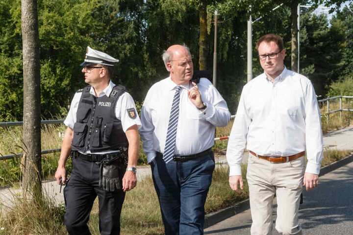 Hans-Joachim Grote (Innenminister Schleswig Holsteins, CDU) (mitte) und Jan Lindenau (Bürgermeister von Lübeck, SPD) (rechts) gehen mit einem Polizeivertreter zum Tatort.