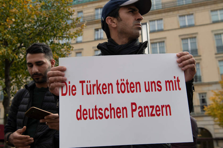Ein Demonstrant hält bei einer Protestaktion gegen die türkische Militäroffensive in Nordsyrien am Pariser Platz ein Plakat mit der Aufschrift "Die Türkei tötet uns mit deutschen Panzern".