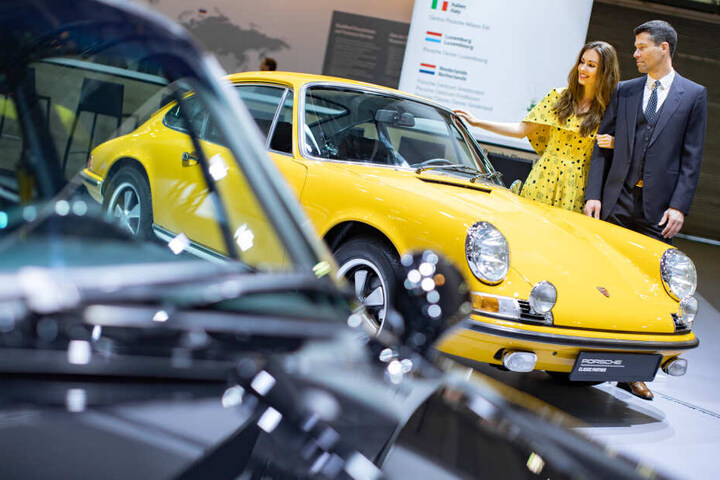 Die Models Vivien und Olaf posieren bei der Techno Classica für Oldtimer und Youngtimer vor einem Porsche 911 aus dem Jahr 1968.