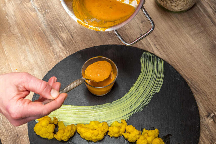 Hier richtet Dana Burde (35) einen Teller mit Curry-Blumenkohl, Tomaten-Kokos-Soße und Avocadocreme an, serviert dazu Hühnchen in Kartoffel-Parmesan-Mantel.