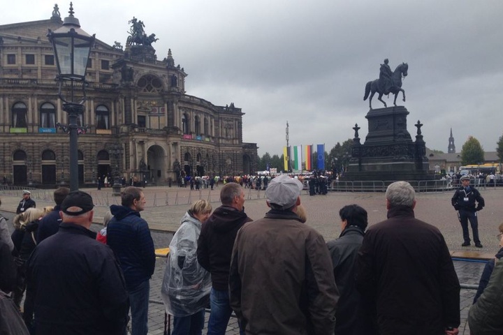 Die Menschen warten auf dem Theaterplatz auf die Politprominenz.