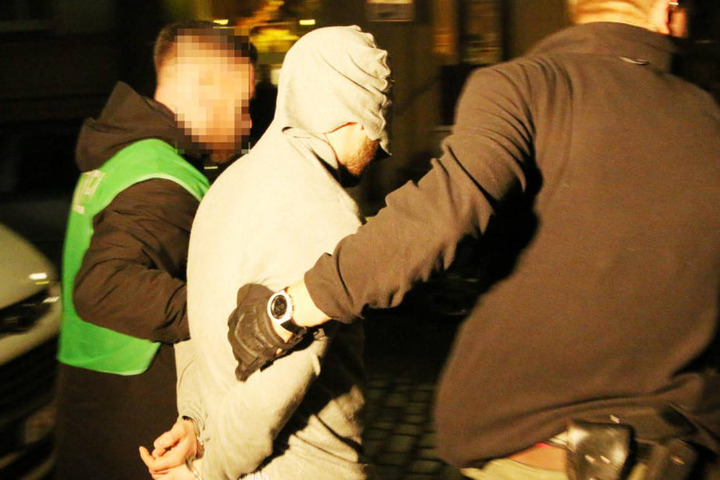 Polizisten führen einen der Verdächtigen ab.