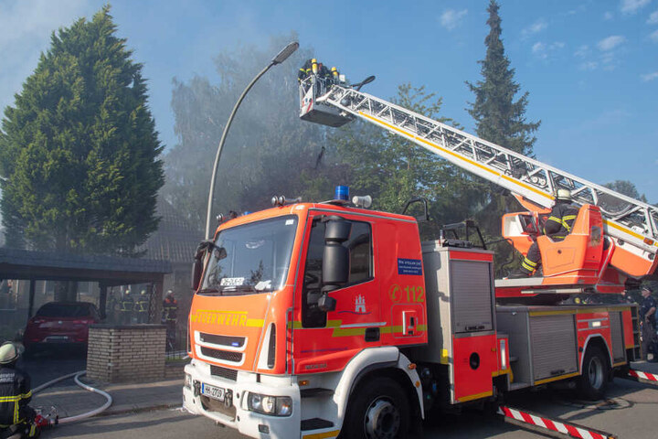 Feuerwehrleute löschen ein brennendes Haus in Hamburg von der Drehleiter aus.