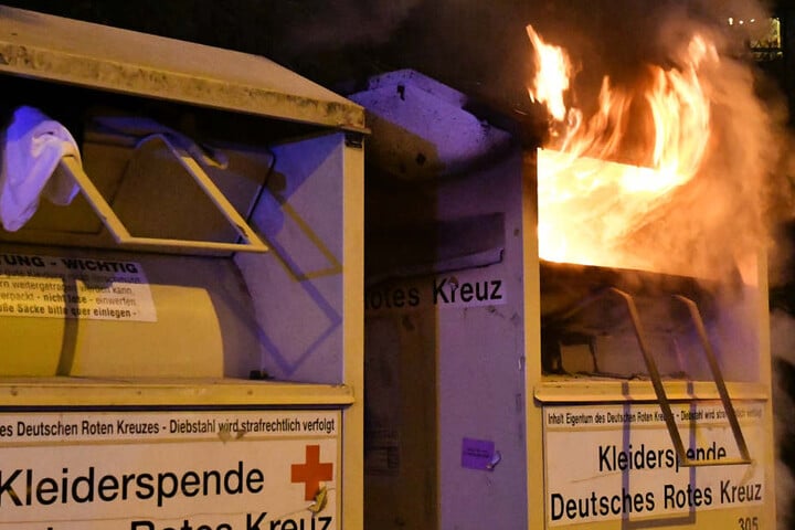 Das Foto zeigt einen Altkleidercontainer, aus dem Flammen heraus lodern.