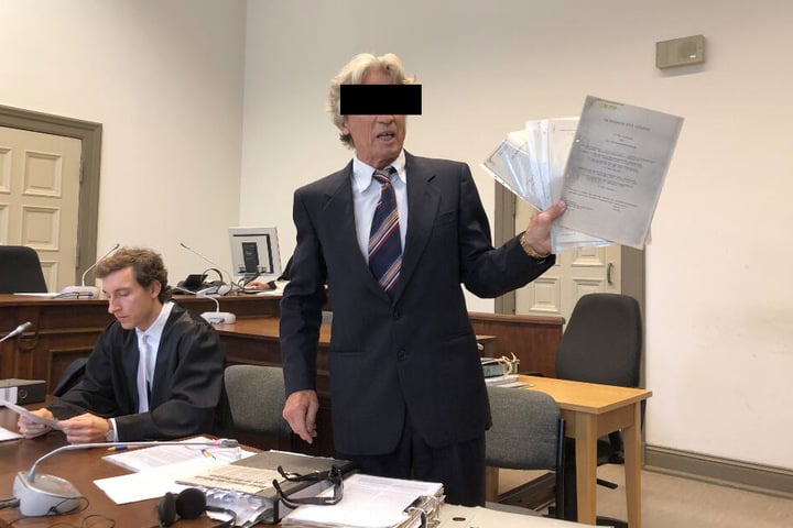 Der Anklagte hält einen Stapel von Papieren in seinen Händen.