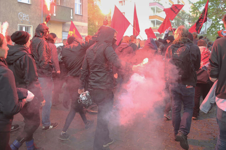 Vermummte Teilnehmer einer Demonstration halten am 30.04.2016 in Wedding brennende Bengalos und Fahnen hoch.