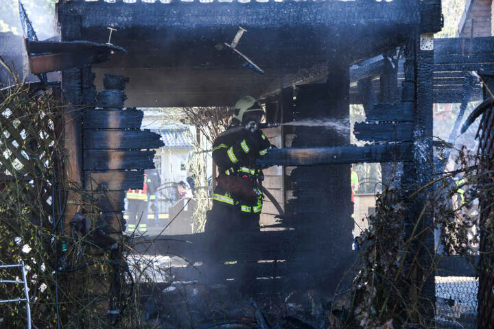 Ein Feuerwehrmann steht im abgebrannten Carport.