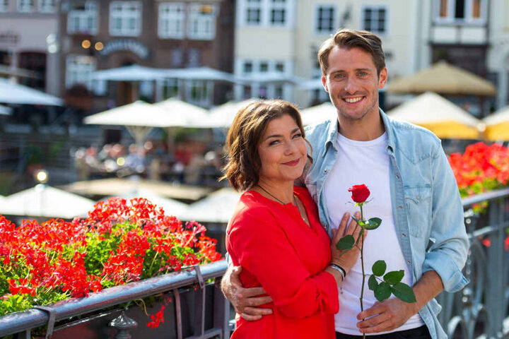 Die beiden Schauspieler, Claudia Schmutzler und Philipp Oliver Baumgarten, stehen am Rande der Dreharbeiten für die ARD-Telenovela "Rote Rosen" für ein Foto zusammen.