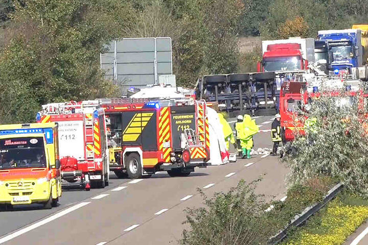 Rettungskräfte stehen um einen umgekippten Gefahrguttransporter herum, der auf der A29 liegt.