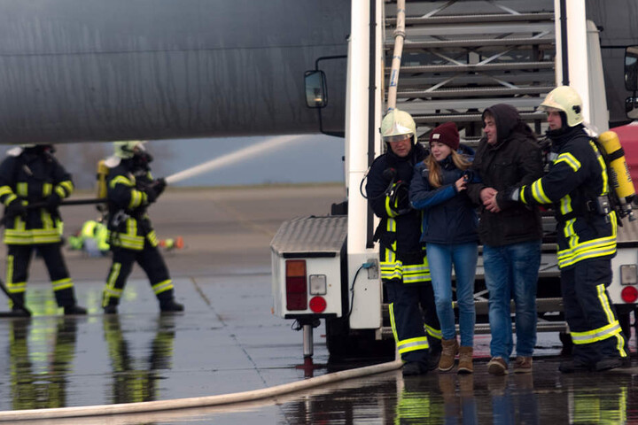 Die Feuerwehrmänner bringen zwei Menschen aus dem Flugzeug.