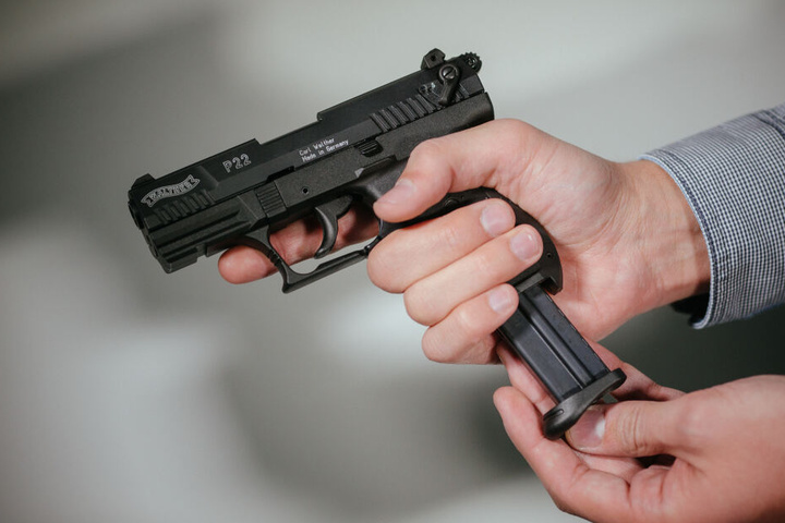 Hände laden eine Schreckschuss-Pistole "Walther P22" mit einem Magazin.