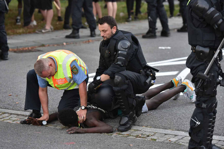 Polizisten nehmen einen lybischen Asylbewerber fest, der aus dem linken Lager zu dem Gegner durchbrechen wollte.