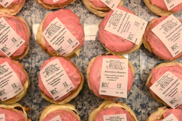 Krapfen mit einem Kassenbon aus Fondant, einer essbaren Zuckermasse liegen in einer Bäckerei in der Auslage.